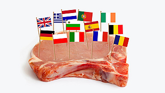 In einem Stück Schweinekottelet stecken Fähnchen mit den Flaggen verschiedener Länder.