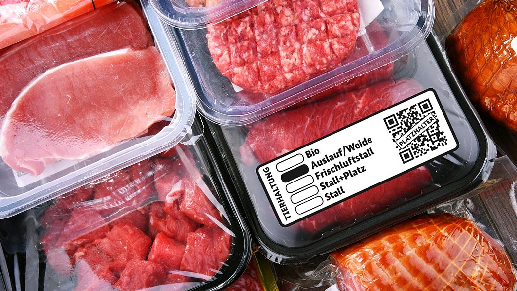 Verschiedene verpackte Fleischprodukte, davor beispielhaft das neue staatliche Tierhaltungskennzeichen