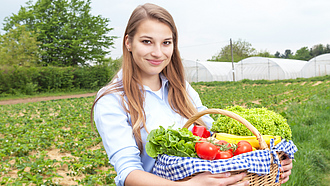 Junge Frau hält Gemüsekorb im Arm