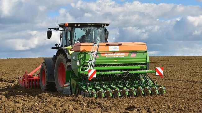 Traktor mit Frontpacker und Sähmaschine bei der Triticalesaat
