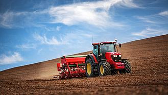 Ein roter Traktor bringt auf einem Feld Samen aus