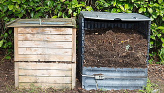 Zwei Komposter nebeneinander in einem Garten.