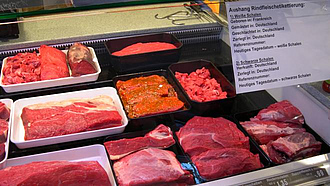 Diverse Stücke rotes Fleisch in der Auslage einer Fleischtheke. In der rechten, oberen Ecke ein Zettel mit den Angaben zur Herkunft.