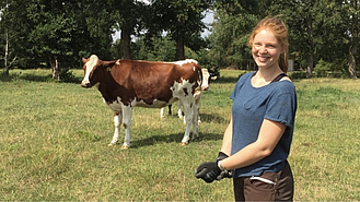 Portraitfoto einer Landwirtin; im Hintergrund eine Kuh