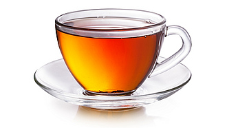 Eine gläserne Tasse mit schwarzem Tee.