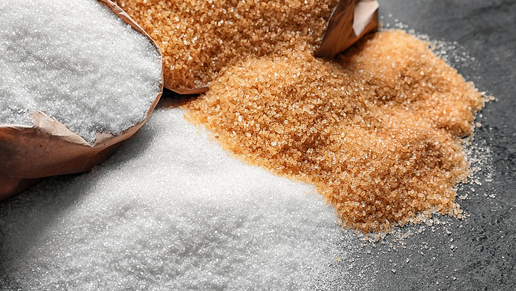 Loser brauner und weißer Haushaltszucker auf einem Tisch.