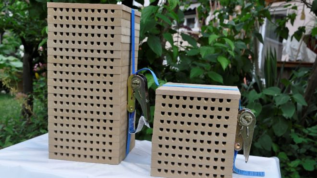 Mehrere Nisthilfen für Wildbienen aus Holz mit Bohrungen