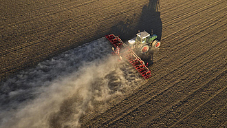 Traktor mit Sämaschinen-Kombination bei der Arbeit auf dem Feld, es staubt sehr