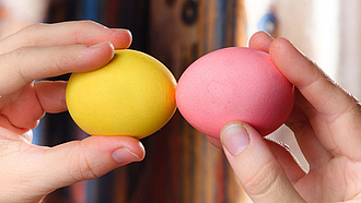Zwei Hände halten jeweils ein Ei und stoßen diese gegeneinander.
