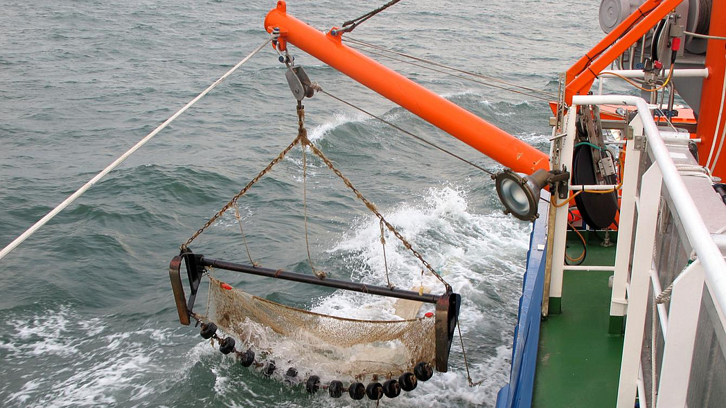 Ein Finschkutter lässt eine Baumkurre zu Wasser