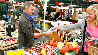 Verkäuferin auf einem Gemüsemarkt bedient die Kasse