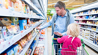 Ein Mann und seine Tochter vor dem Kühlregal im Supermarkt.