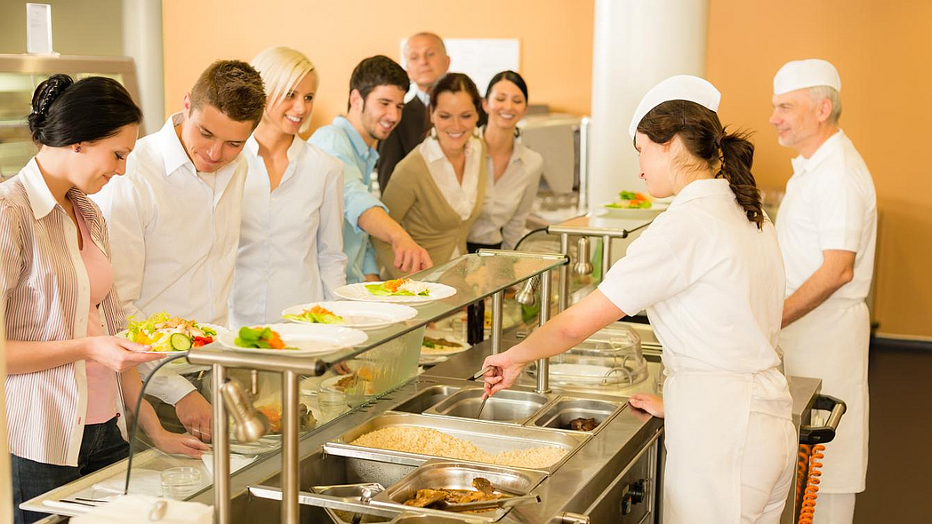 Menschen an der Essensausgabe in einer Kantine