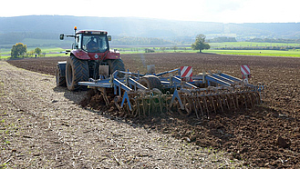 Traktor mit Grubber bei der Bearbeitung von Ackerland, auf dem Mais stand.