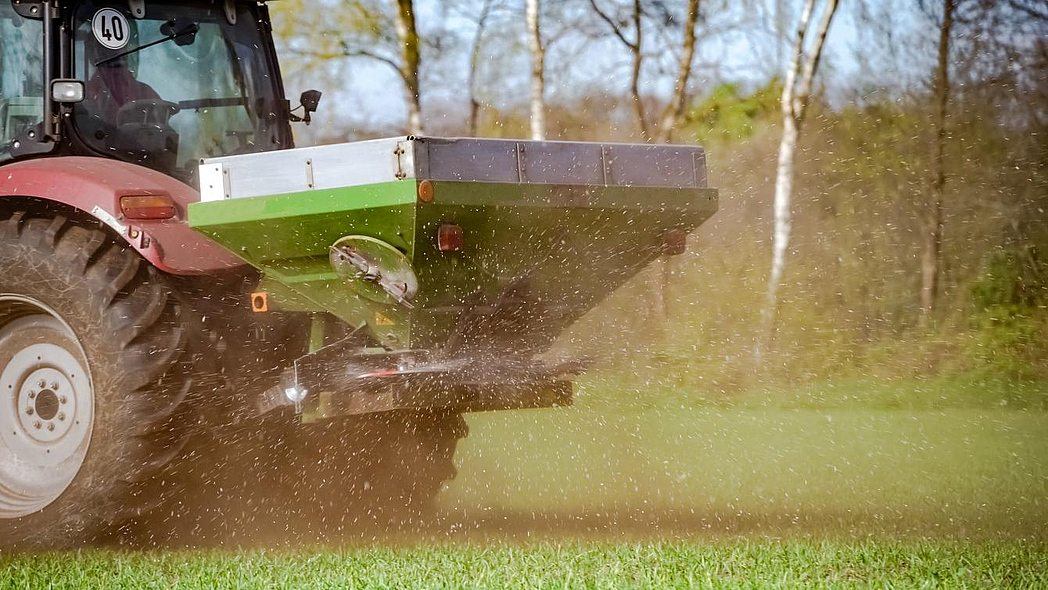 Traktor mit Mineraldüngerstreuer im Einsatz auf dem Feld