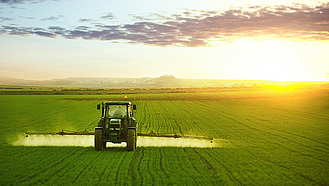 Ein Traktor bringt auf dem Feld Pflanzenschutzmittel aus