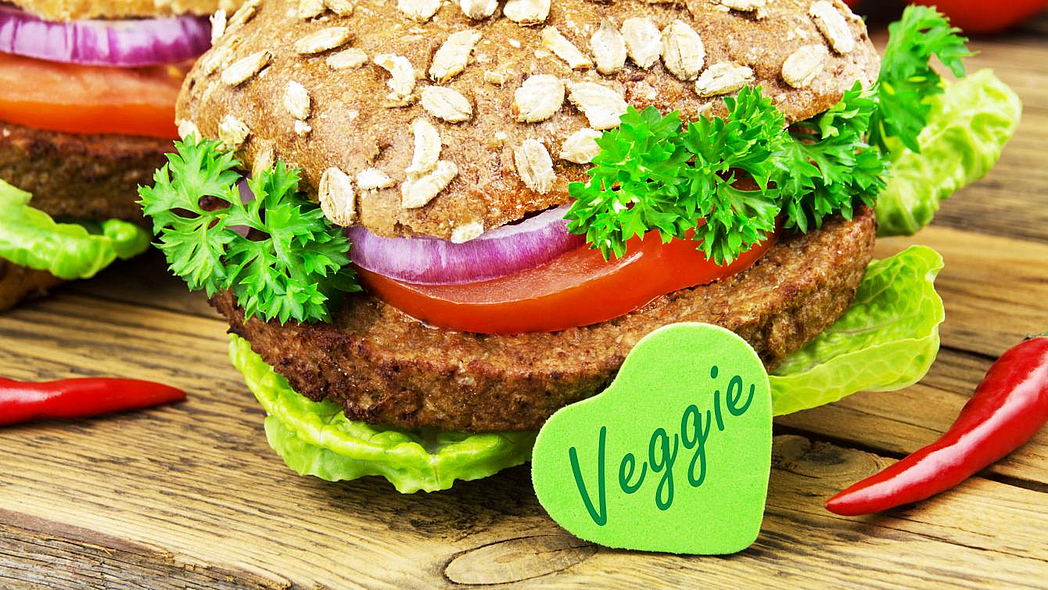 Burger mit vegetarischem Patty und garniert mit Salat, davor ein herzförmiges Schildchen "Veggie"