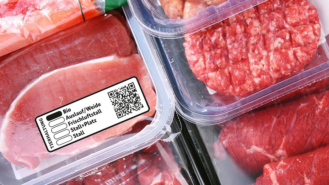 Verschiedene verpackte Fleischprodukte, davor beispielhaft das neue staatliche Tierhaltungskennzeichen