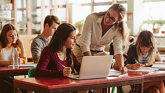 Lehrerin mit Schülerinnen und Schülern im Klassenraum