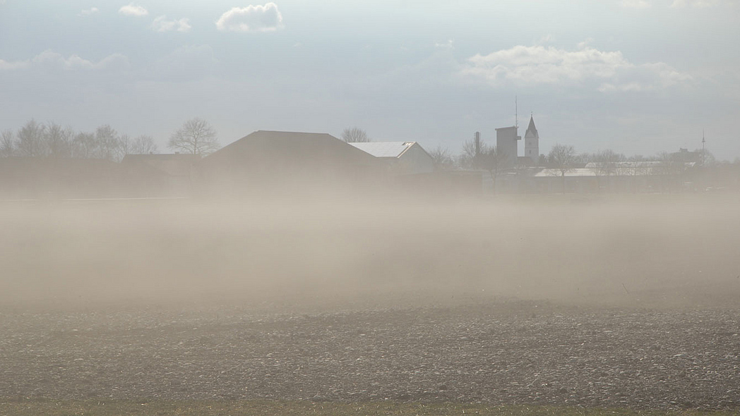 Bodenpartikel steigen von einem erodierten Feld auf