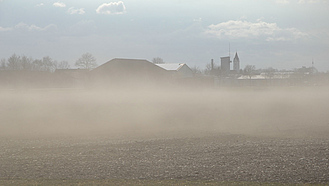 Bodenpartikel steigen von einem erodierten Feld auf