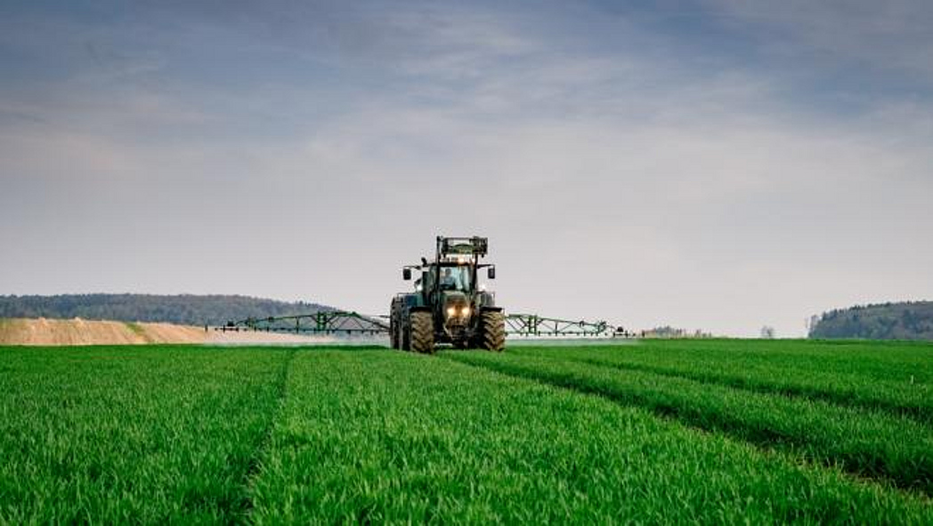 Traktor mit Pflanzenschutzspritze auf dem Feld