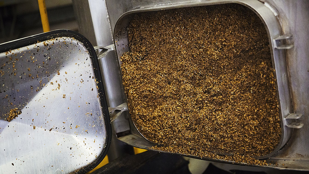 Offene Tür eines großen Edelstahlkessels in einer Brauerei, der Biertreber enthält.