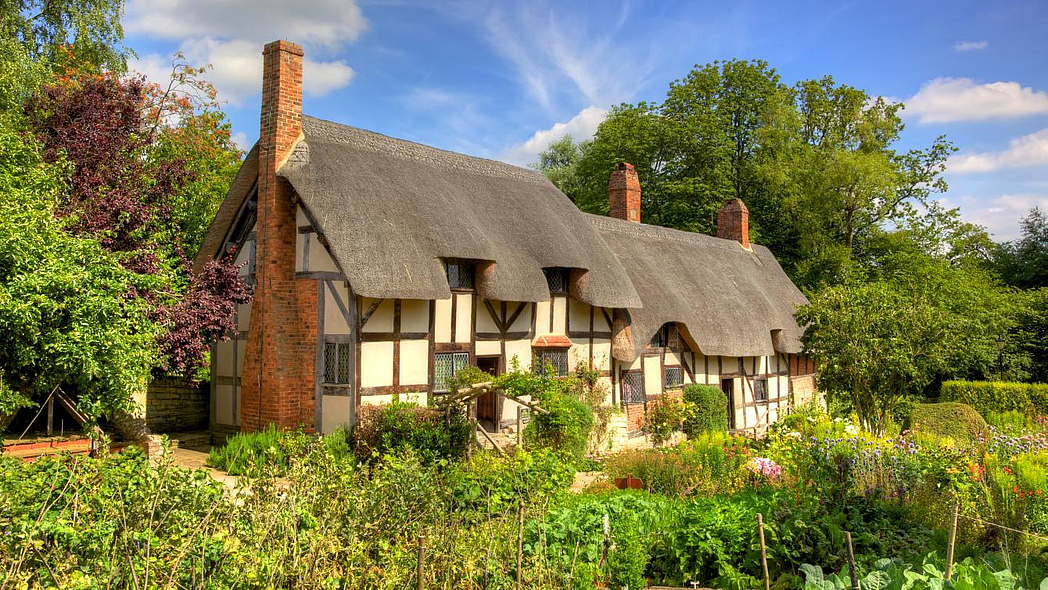 Schönes altes Bauernhaus, davor ein üppiger Bauerngarten mit Gemüse, Kräutern und Blumen