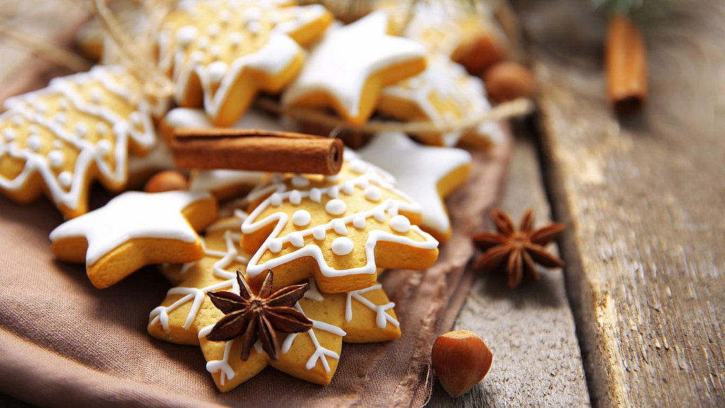 Weihnachtsgebäck liegt mit Sternanis und Zimt auf einem Holztisch.