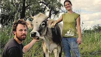 Landwirtin und Landwirt mit Kuh